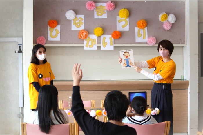 絵本読み聞かせ会の写真。アナウンサー2名が子供たちに絵本を読み聞かせている